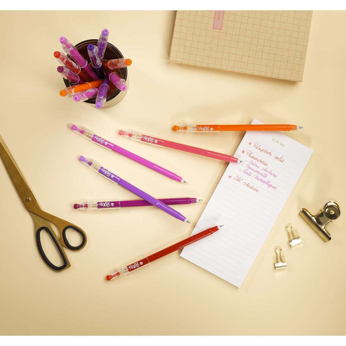  a to-do list written with colourful FriXion Stick Erasable Gel Pen, with pink, red, purple and wine red pens laying next to a scissors