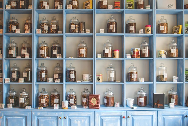 Tea and herb storage jars on shelves with labels written with erasable pens