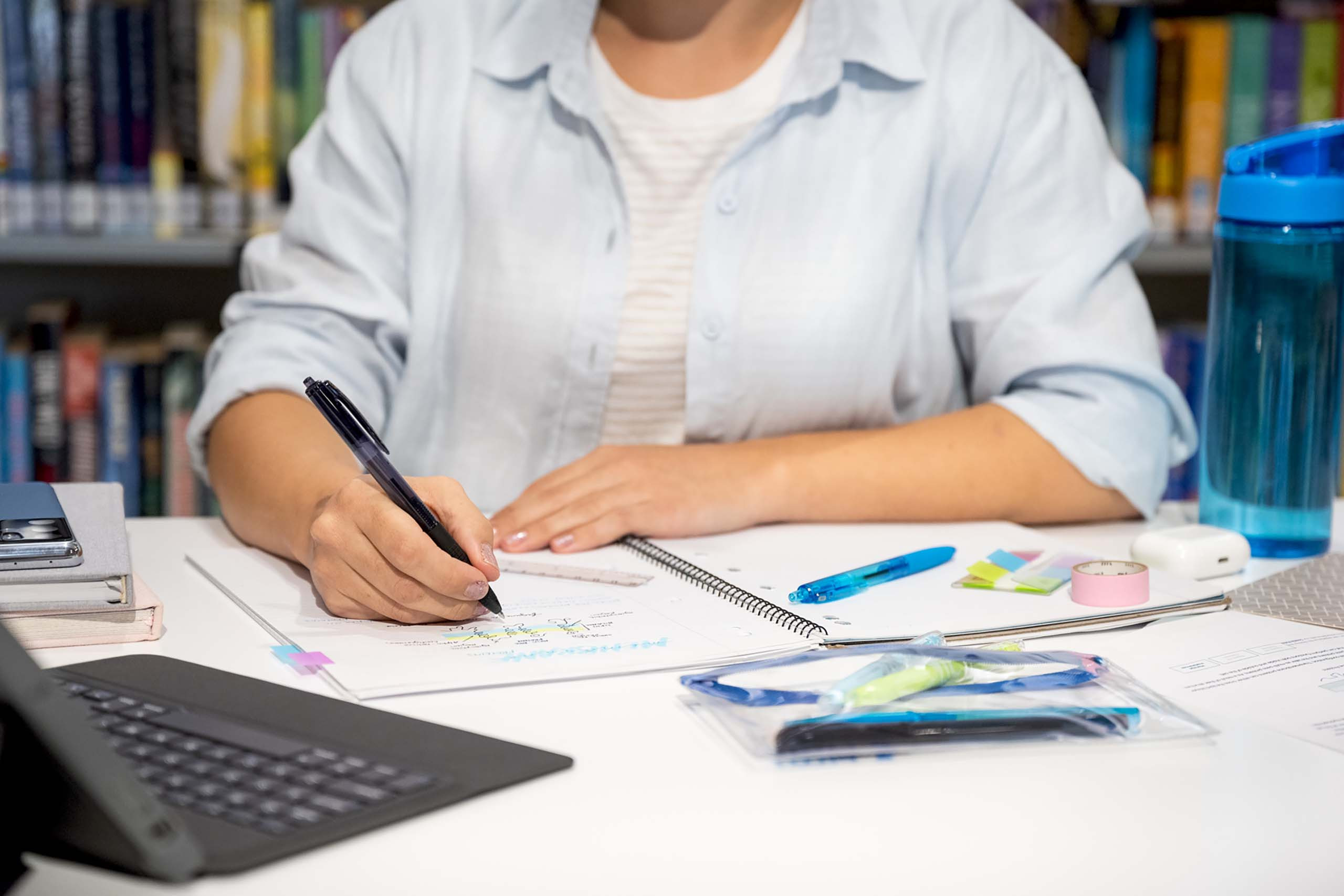 A student writing with a PILOT Super Grip G retractable pen in her note book at a study desk, capturing its practical use in everyday note-taking.