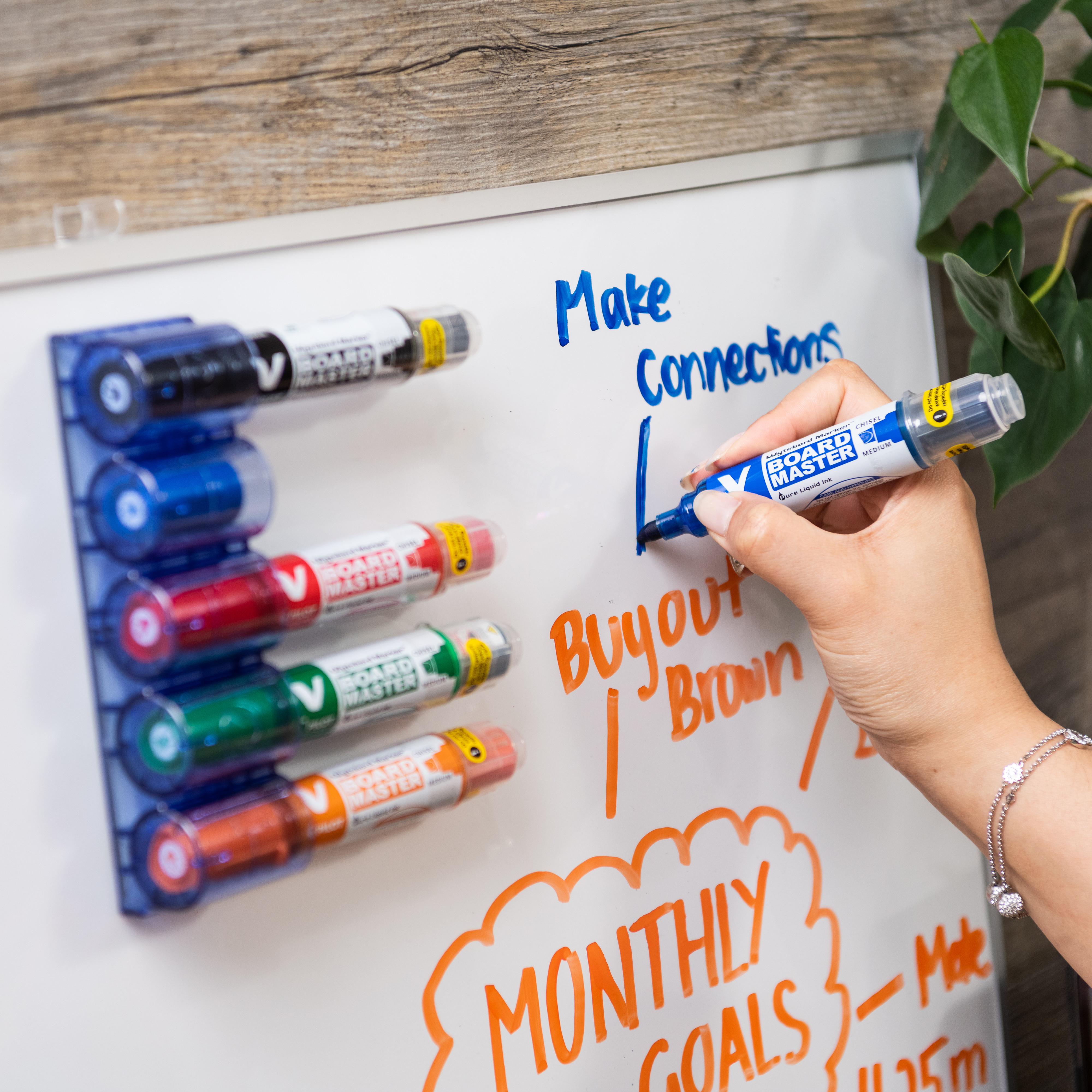 Pilot V Board Master refillable markers in a blue holder on a whiteboard, ideal for sustainable use in offices, schools, and professional settings.