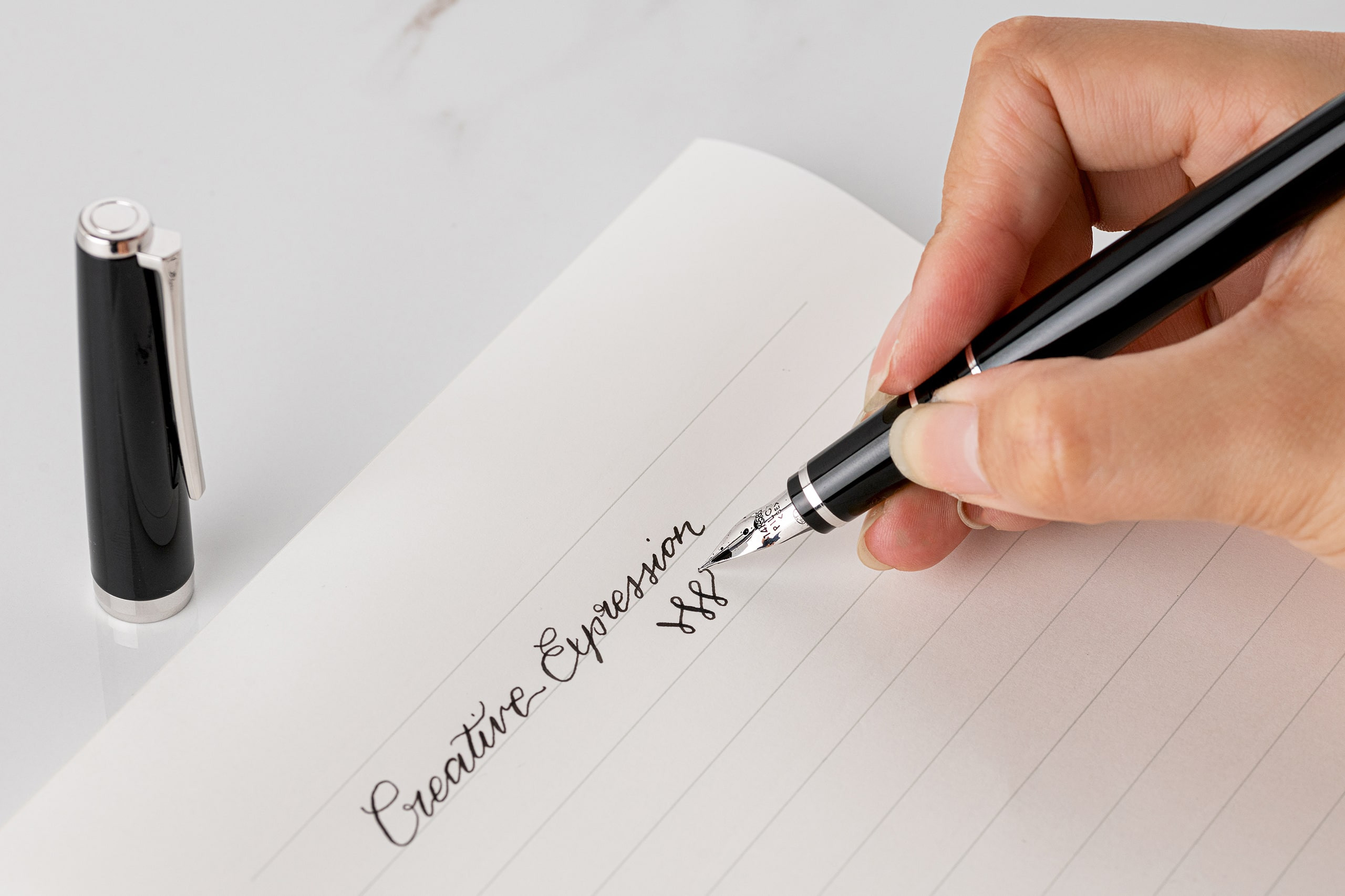 Handwriting the phrase 'Creative Expression' with a Falcon Fountain pen, exemplifying the elegance of calligraphy writing.