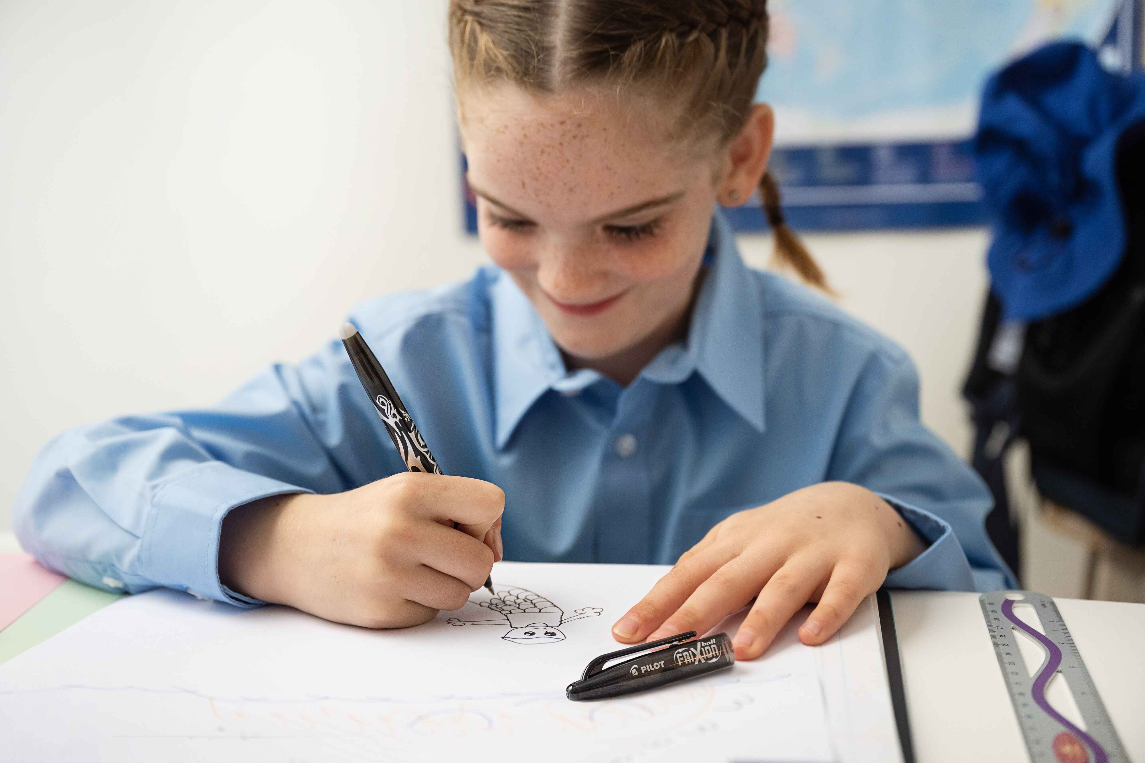 A child using an Erasable Gel Pen in school to draw a picture, highlighting the benefit of erasable pens for children as it allows for mistakes. 