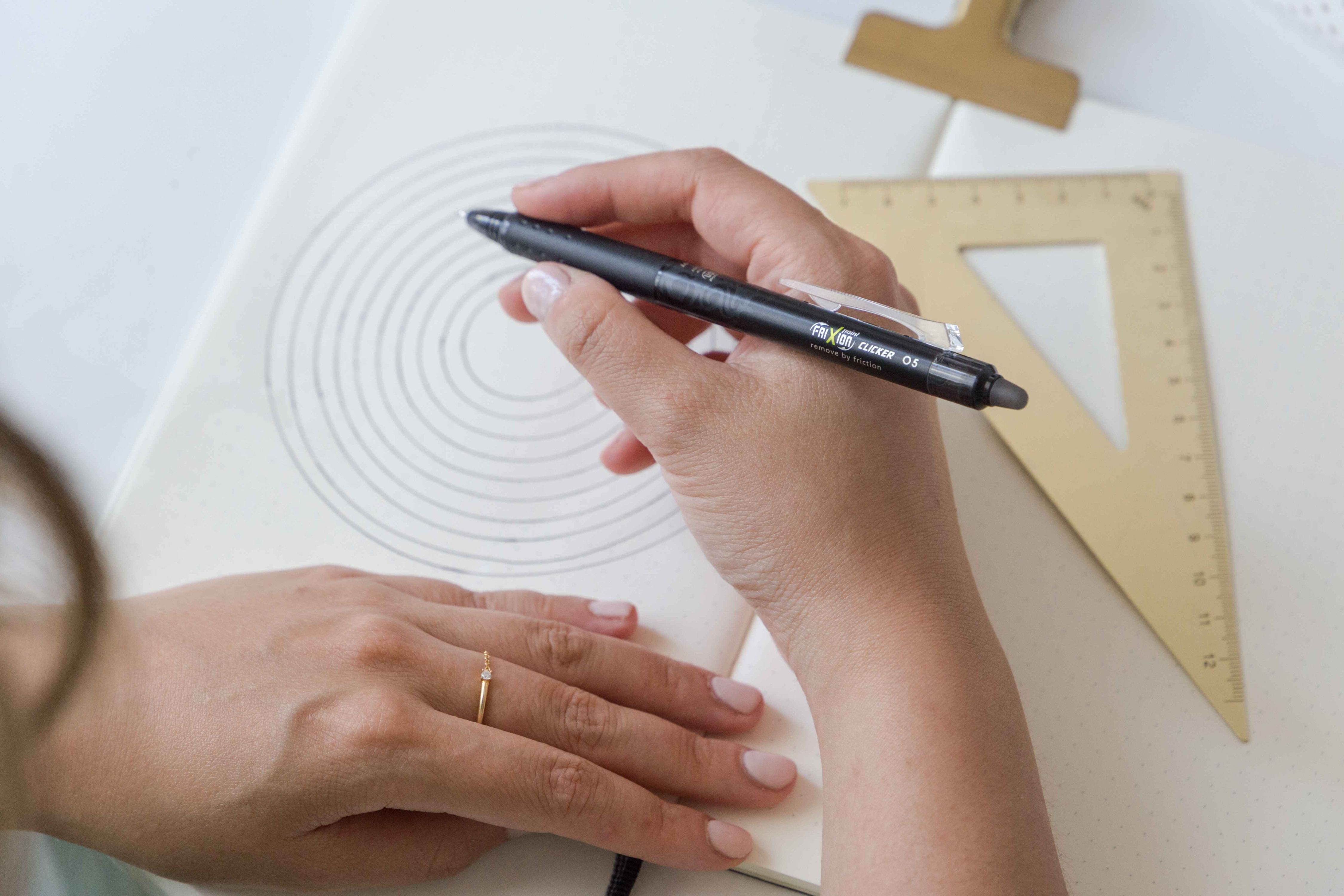 Woman sketching using a black FriXion Clicker erasable pen.