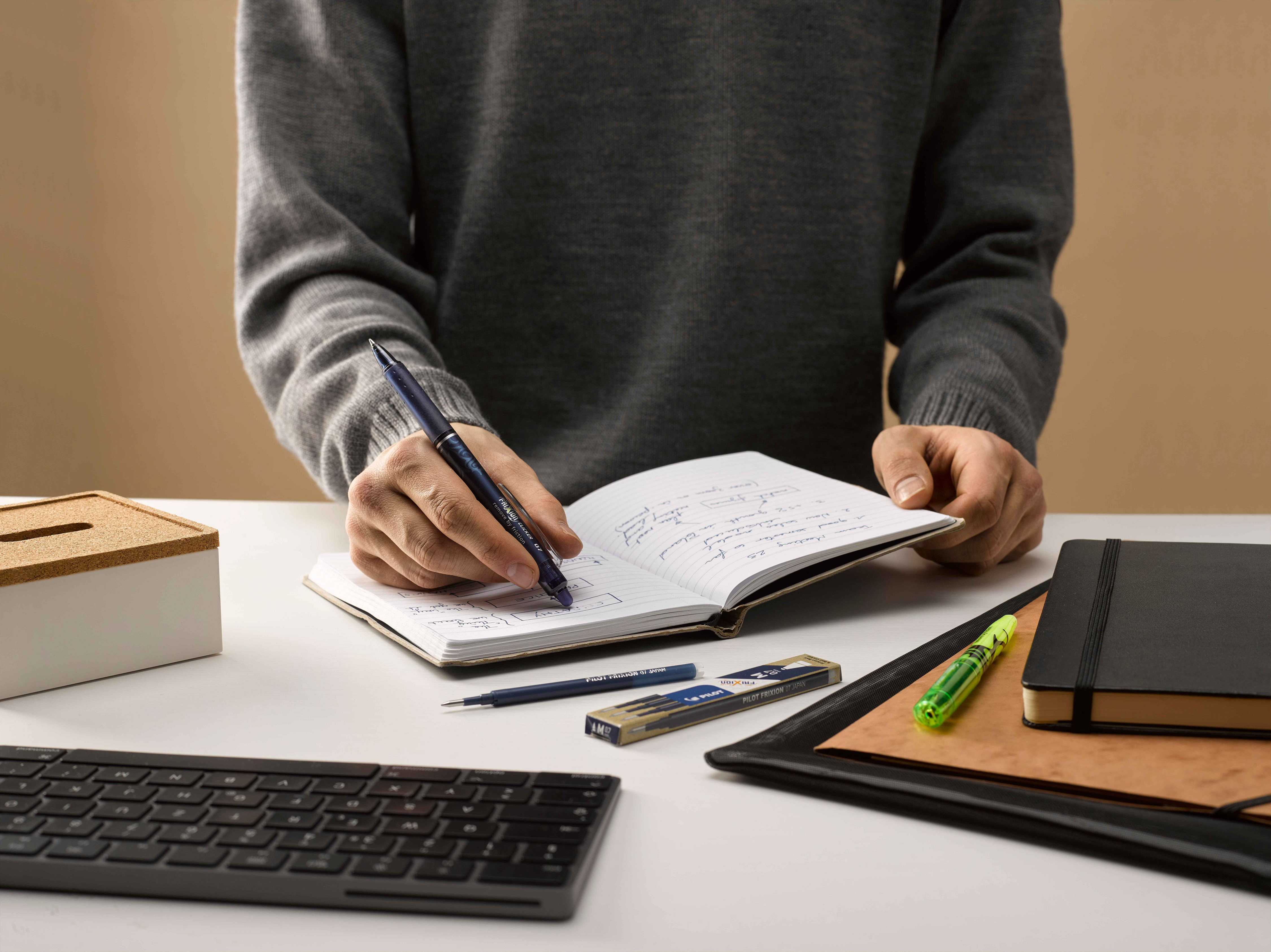 Professional erasing an error in his notepad, using the built-in eraser on his erasable pen. 