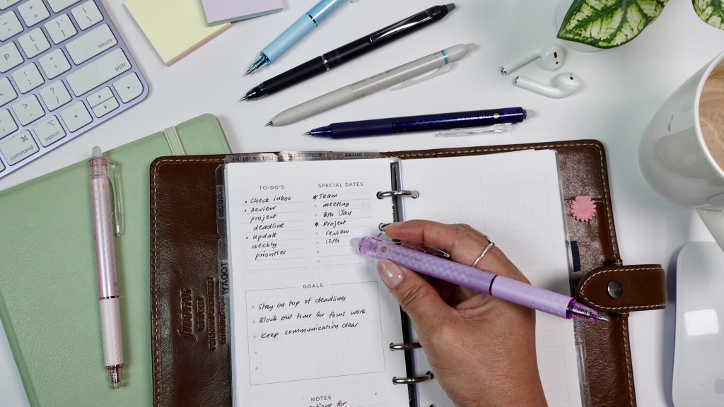 Hand erasing a completed task from a planner page using a PILOT FriXion pen.
