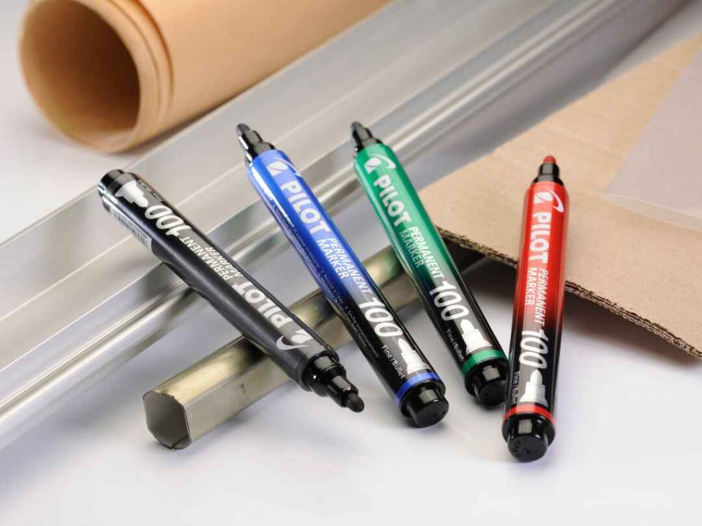 Four Permanent Marker 100’s in black, blue, green and red in an industrial setting.