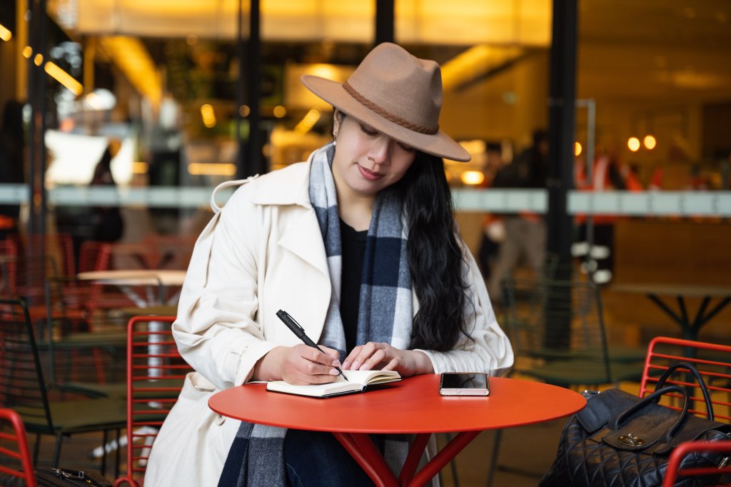 Woman practicing mindful writing at a café using a premium fountain pen.