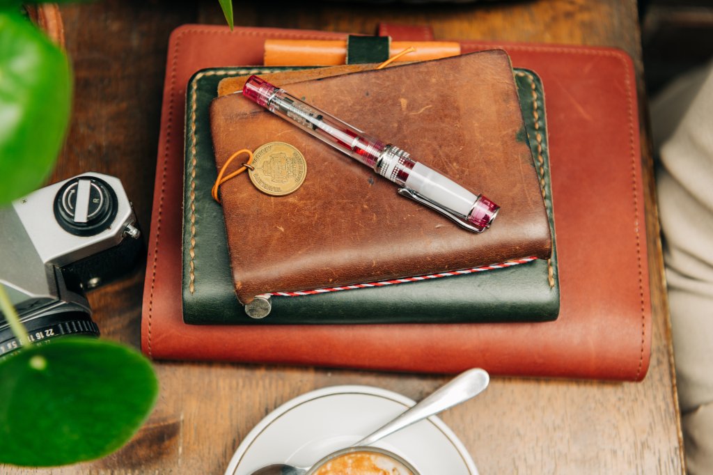 PILOT Pen Premium Writing pen on leather journals in a cafe.