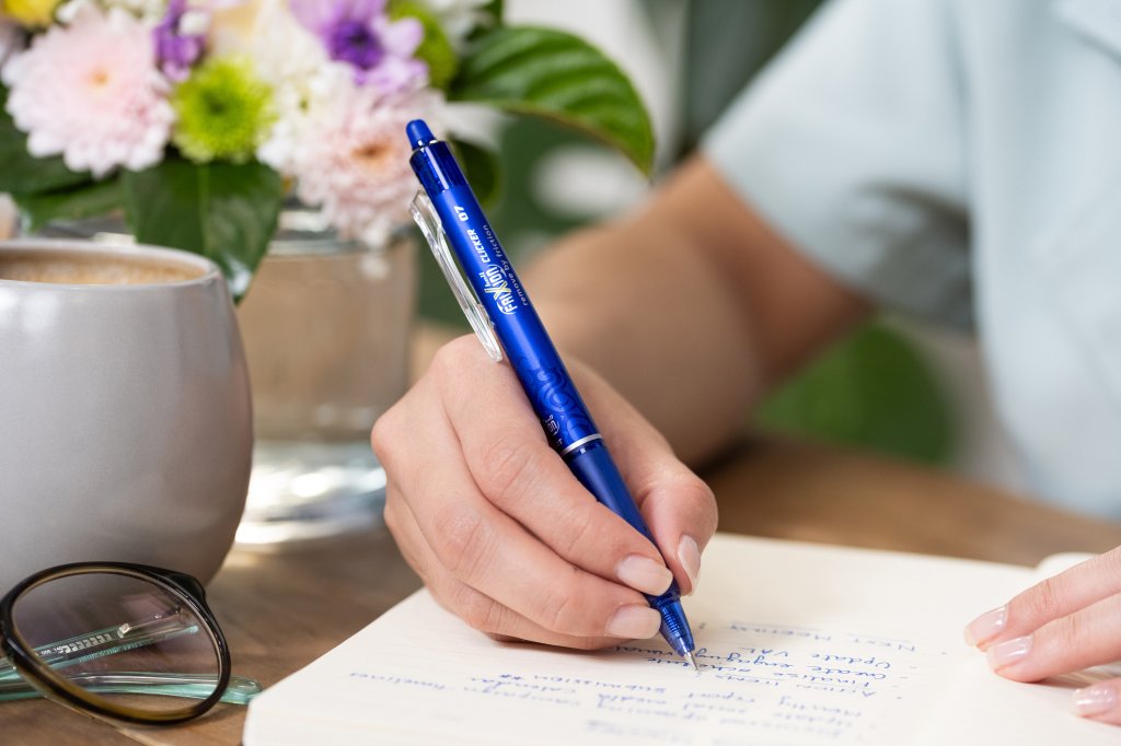 Close up of a PILOT FriXion Erasable Clicker writing in a notebook showing why is writing better than typing.