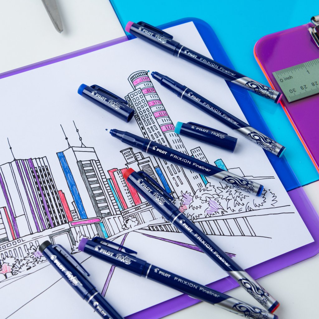 Pilot FriXion Erasable Fineliners, on a desk next to a ruler, over a colourful sketch of a city skyline.